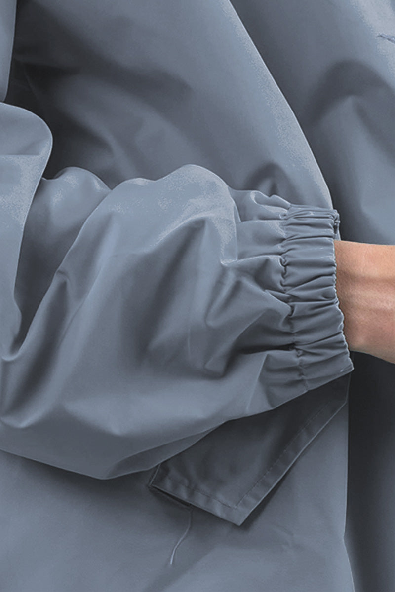 The image depicts a close-up of a person wearing The Windbreaker Jacket's POWDER BLUE WINDBREAKER. The focus is on the sleeve, which features an elastic cuff. With their arm slightly bent and part of their hand visible, the jacket exhibits a matte finish.